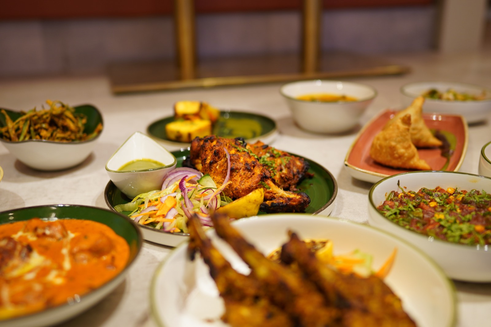 Tandoori grills, curries and small plates laid out on a table at Elaichai